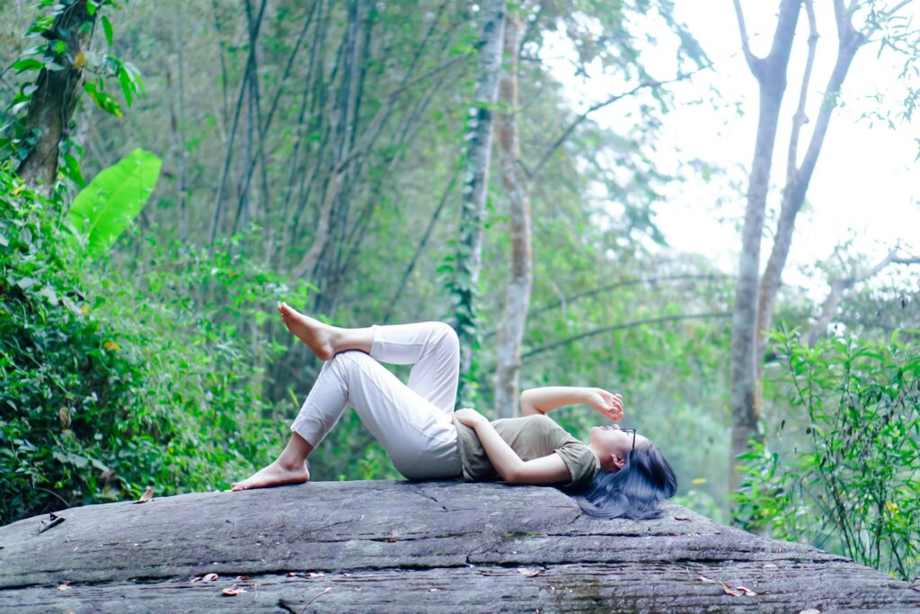 Woman lying on log in forest relaxing